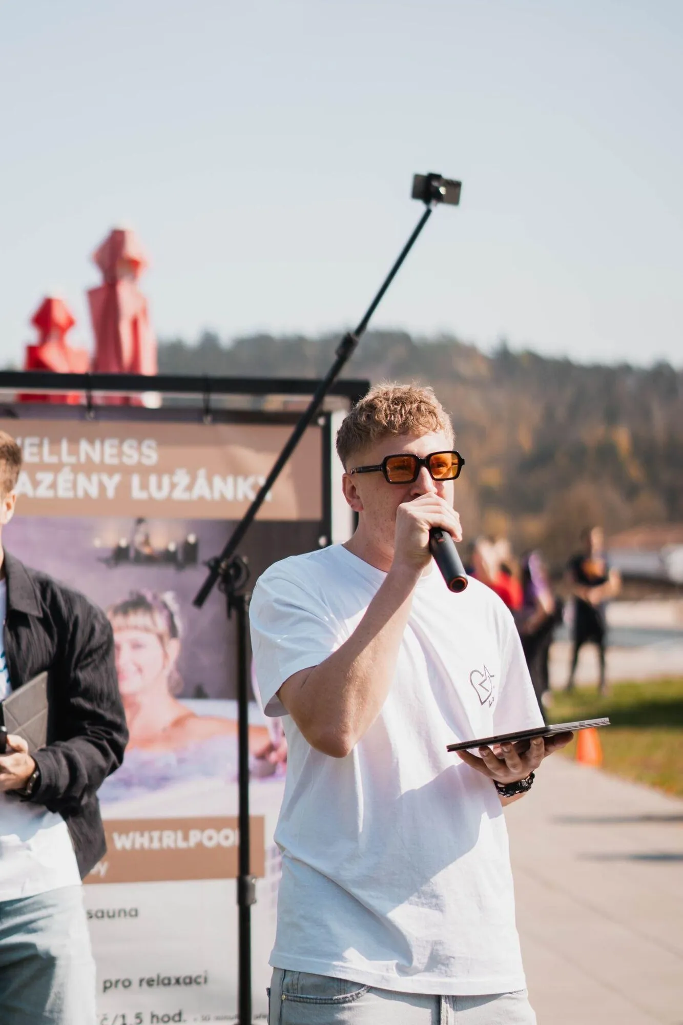 Kryštof s mikrofonem a tabletem v bílém tričku