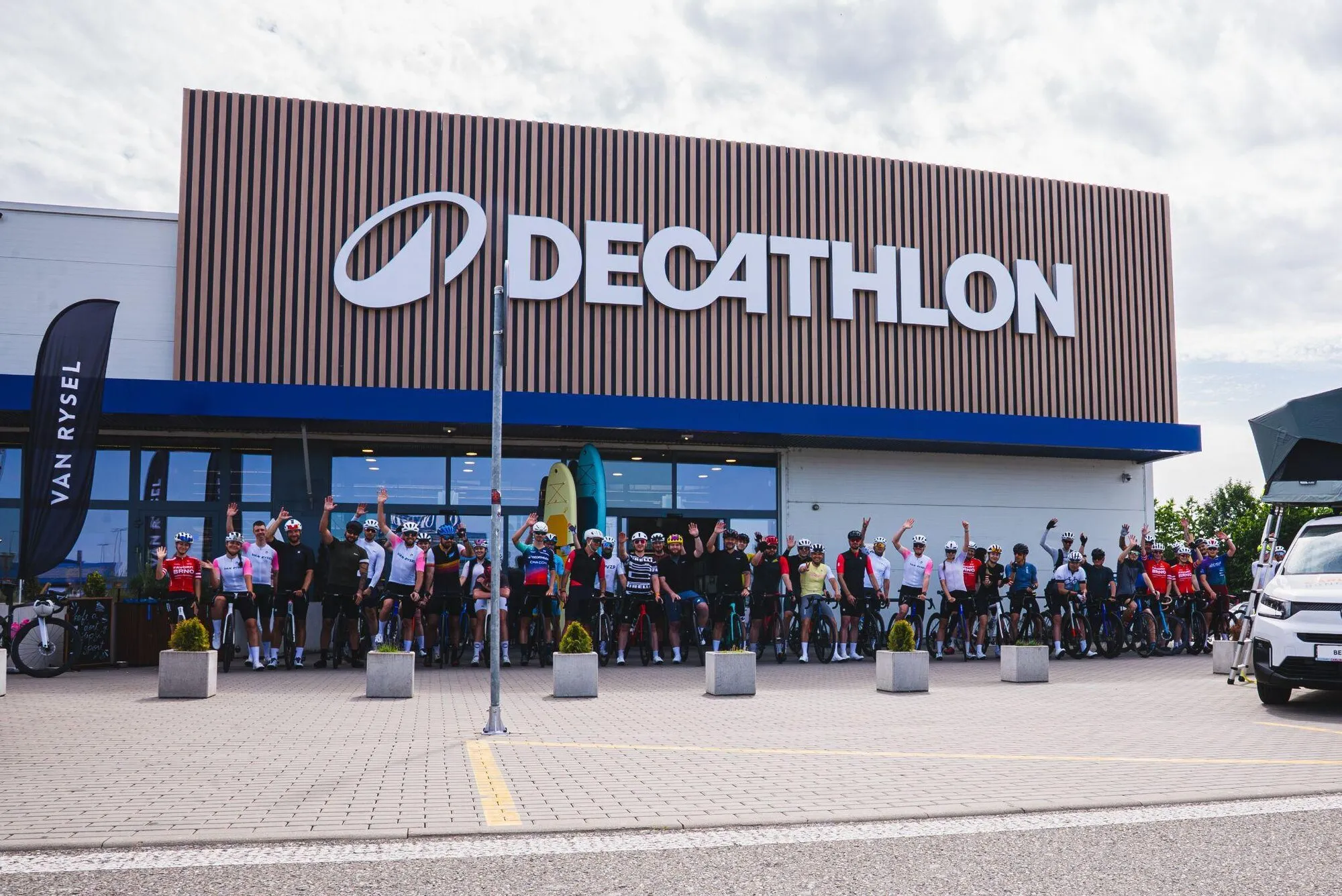 Peloton cyklistů před prodejnou Decathlon