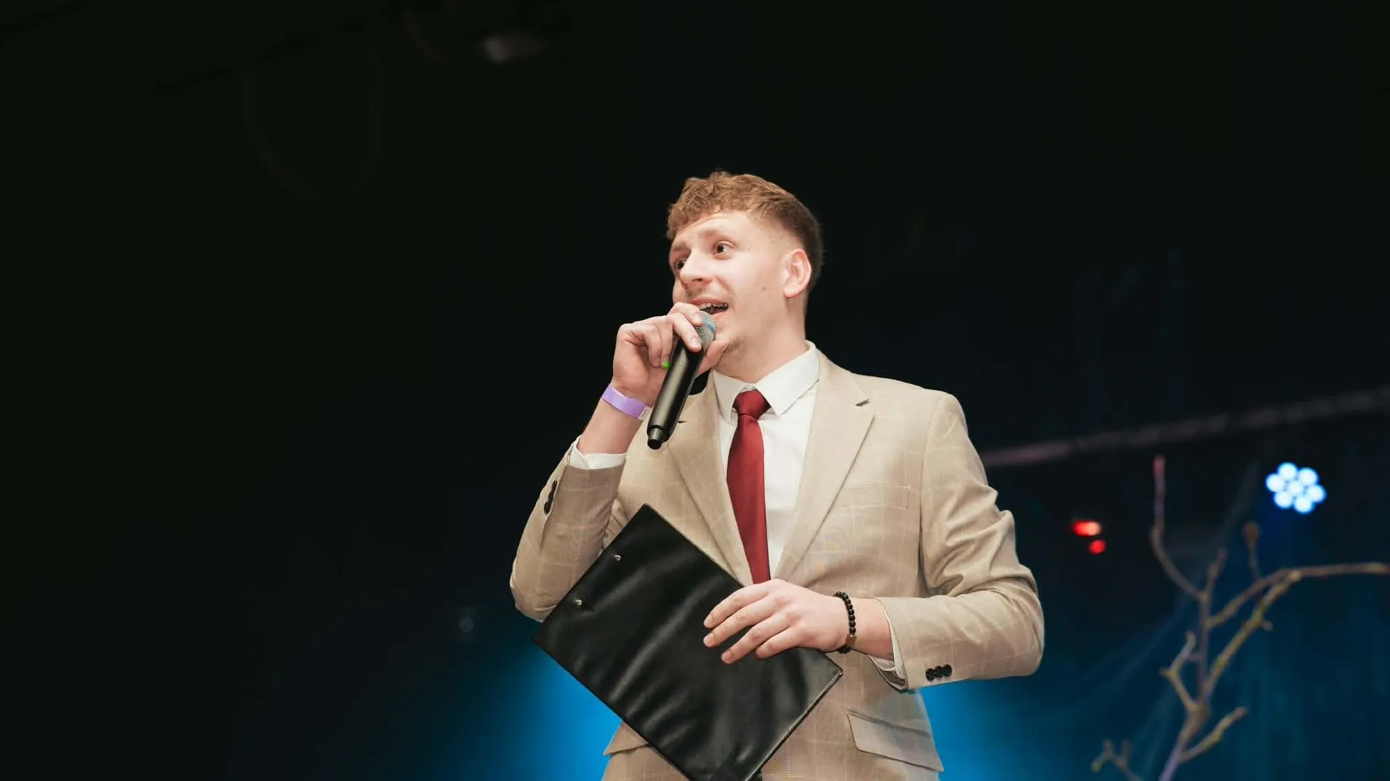 Kryštof v obleku s mikrofonem na plese MENDELU